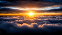 Dramatic sunrise above fluffy white clouds with golden orange sky reflecting warm light across peaceful cloudscape for meditation and inspiration content.