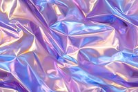 Holographic iridescent crumpled foil texture in pink and blue colors creating abstract futuristic background with metallic shine and wrinkled surface effect.