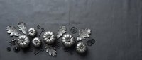 Metal decorative flowers and leaves arrangement on dark textured background for crafting and design projects.