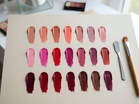 Lipstick color palette swatches on white paper showing various shades from nude to deep burgundy for makeup artist cosmetic selection and beauty testing.