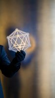 Hand holding glowing geometric wireframe sphere with interconnected lines, representing network connectivity, data science, artificial intelligence, and digital innovation against blurred background.