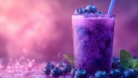Fresh blueberry smoothie with frozen berries and mint leaves on purple background with bokeh effect, cold summer drink for healthy lifestyle.