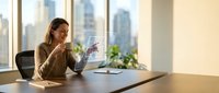 Professional businesswoman analyzing financial charts in modern office with city skyline view during golden hour lighting for corporate presentations.