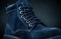 Blue suede work boot with laces isolated on dark background, suitable for footwear advertising, e-commerce, and fashion catalogs.