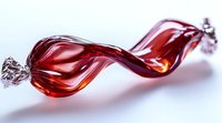 Red twisted glass candy wrapper with metallic ends on white background, elegant abstract shape capturing light and reflection for decorative design.
