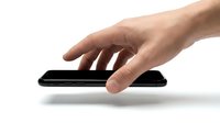 Close-up of a hand with light skin tone touching a black smartphone on white background. Suitable for technology, mobile apps, communication, and digital device concepts.