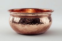 Hammered copper bowl with polished rim and textured surface reflecting warm metallic tones against neutral background. Traditional handcrafted vessel for home decor.