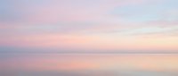 Serene dawn seascape with soft pink and lavender hues reflecting on calm water, capturing tranquil morning atmosphere for wellness and meditation content.