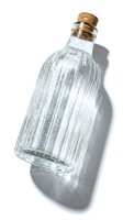 Ribbed clear glass bottle with cork stopper casting dramatic shadow on white background, vintage style container for beverages, oils, or decor.