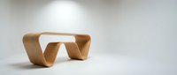 Modern curved wooden bench with flowing organic design on white background for contemporary interior furniture showcase.