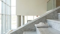 Modern marble staircase with glass railings in contemporary building interior featuring natural light and minimalist architectural design.