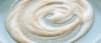 Creamy latte art spiral swirl in white coffee cup with foam texture and bubbles creating elegant cafe beverage pattern for morning drink concepts.