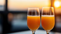 Two glasses of fresh orange juice against blurred sunset background, perfect for breakfast, brunch, or healthy lifestyle concepts.