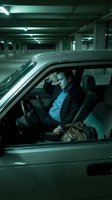 Stressed businessman sitting in car in underground parking garage holding head in hands showing work pressure and mental fatigue after long day.