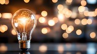 Glowing light bulb against blurred warm bokeh background creates magical atmosphere of inspiration and creativity. Concept of bright ideas and innovation.