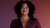 Young African American woman with curly hair smiling confidently in burgundy blouse against gradient background for business and lifestyle content.