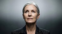 Mature woman with gray hair and fair complexion wearing dark blazer against neutral background, professional portrait for business and corporate use.