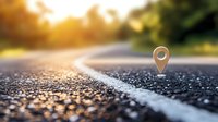 Location pin marker on empty asphalt road at sunset with bokeh light effect, white line marking and blurred nature background, concept of journey and navigation.