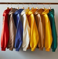 Colorful sweatshirts hanging on wooden rack against white wall. Collection of casual cotton hoodies in red, beige, navy, cream, yellow, brown and green shades.