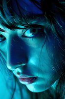 Close-up portrait of young woman with tousled hair in dramatic blue lighting. Moody cinematic style for fashion, beauty and artistic projects.