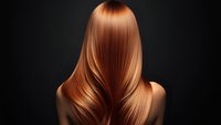 Back view of long straight copper hair with smooth glossy texture on dark background, showing professional hair care and styling results.