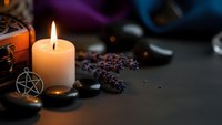 Mystical altar setup with burning candle, pentagram pendant, dried lavender, crystals and wooden box for spiritual rituals and witchcraft practices.