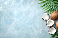 Fresh coconuts and palm leaves on blue water background with ripple effect and copy space for summer beach concept design and text placement.