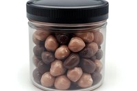 Chocolate covered nuts or candy in clear plastic jar with black lid. Mixed dark and milk chocolate coated treats for confectionery and candy shop display.