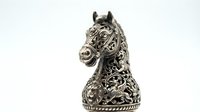 Ornate metallic horse head sculpture with intricate filigree detailing and decorative patterns, isolated on white background for design projects.