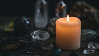 Orange candle burning on mystical altar with crystals and tarot cards creating atmospheric spiritual meditation scene for wellness and divination practices.