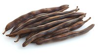 Dried carob pods arranged on white background showing natural brown color and curved shape, organic healthy alternative sweetener and food ingredient.