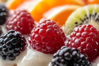 Fresh mixed berries and fruit slices arranged on white surface. Colorful assortment of raspberries, blackberries and kiwi for healthy eating and nutrition concepts.