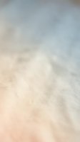 Soft-focused sandy beach surface with shallow depth of field, transitioning from warm beige sand in foreground to blurred blue sky and ocean backdrop, ideal for travel and vacation concepts.