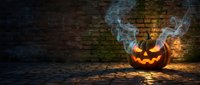Glowing jack-o-lantern with smoke against brick wall at night, suitable for Halloween decorations, seasonal marketing, and festive event promotions.
