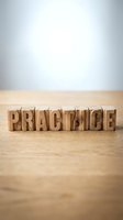 Wooden letter blocks spelling PRACTICE on natural wood surface against neutral background for business training and skill development concepts.