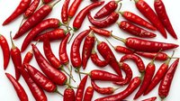 Red hot chili peppers scattered on white background, fresh spicy ingredients for cooking, food photography, isolated for design use.