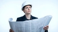 Engineer or architect with light skin tone reviewing construction blueprints while wearing white hard hat and dark jacket, looking upward thoughtfully against white background.