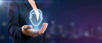 Businessman in dark suit holding glowing shield icon symbolizing cybersecurity, data protection, and network security for business technology concepts.