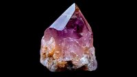 Raw pink tourmaline crystal with rough edges and natural formation shows vibrant magenta and orange hues against dark background, displaying mineral's natural beauty.