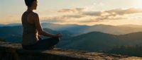 Young woman meditating in lotus pose on mountain cliff during golden hour sunset with layered hills in background creating peaceful mindfulness scene.