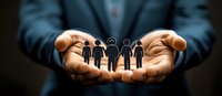 Business person holding paper cutout figures in cupped hands representing team leadership, workforce management and human resources concept on dark background.