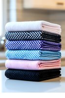 Stack of colorful folded kitchen towels with checkered and solid patterns arranged neatly on counter for home textile and cleaning supplies concept.