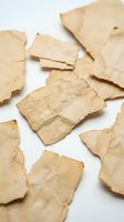 Aged parchment paper pieces scattered on white background, torn vintage manuscript fragments for historical design projects and creative layouts.