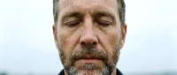 Middle-aged Caucasian man with salt-and-pepper beard and closed eyes, displaying calm, contemplative expression. Suitable for wellness, mindfulness, mental health, and lifestyle editorial use.