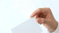 Hand holding blank white trapezoid card or paper against light background, suitable for mockups, presentations, and advertising designs.