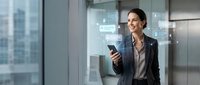 Confident young Caucasian businesswoman holding smartphone with glowing digital chat icons, standing in modern office, smiling, communication and technology concept.