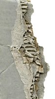 Weathered concrete wall with peeling plaster and exposed layers revealing deteriorated surface texture, suitable for grunge backgrounds and industrial design projects.