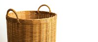 Wicker laundry basket with handles isolated on white background for home organization and storage solutions in rustic natural style decor.