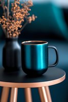 Metallic turquoise coffee mug on copper-colored table with dried flowers in black vase against dark background, modern minimalist style composition.