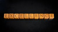 Wooden letter blocks spelling EXCELLENCE on dark background for business motivation and success concepts.
